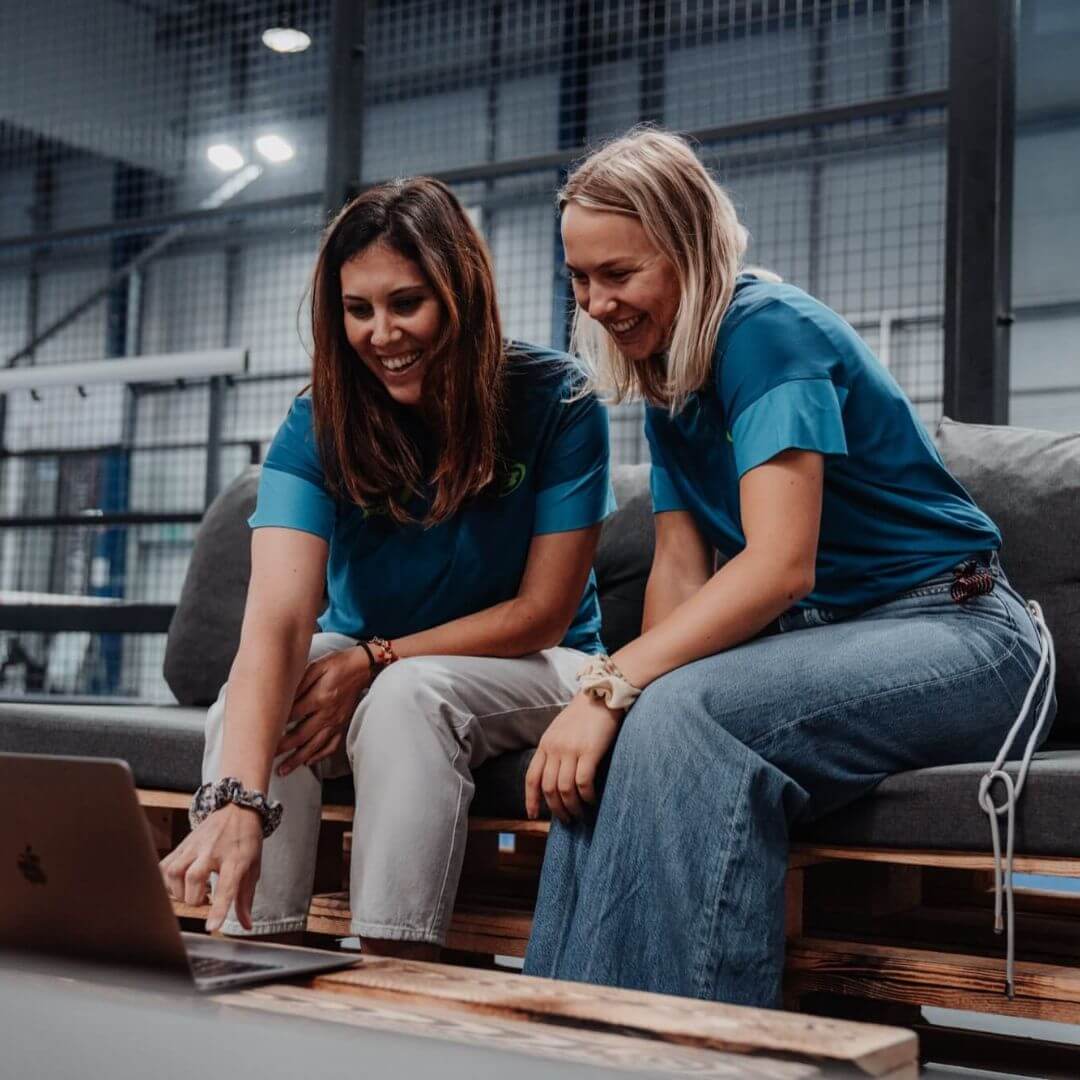 Begoña Fernandez Nuevo und Nina Laudien sitzen am Padelcourt und schauen in den Laptop